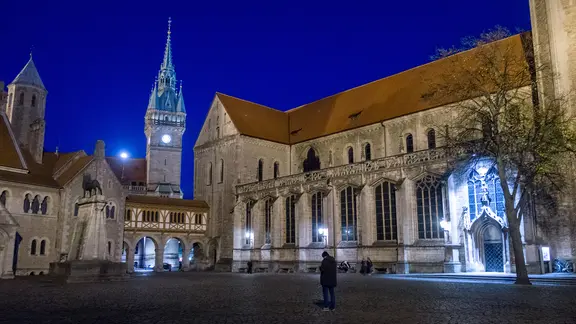 Der Burgplatz mit der Burg Dankwarderode (l-r), dem Rathaus und dem Braunschweiger Dom am frühen Abend. Nur wenige Menschen auf dem Platz.