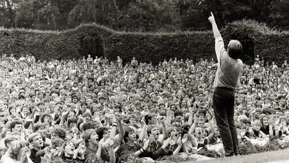 Herbert Grönemeyer reckt bei einem Auftritt im Hamburger Stadtpark 1986 vor Tausenden Fans den Arm nach oben.