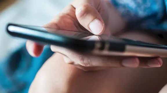 Eine Person hält ein Handy in der Hand.