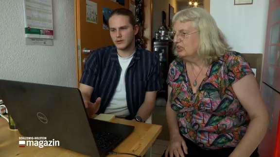 Zwei Personen sitzen vor einem Laptop