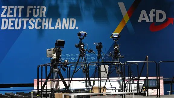 Kameras vor blauem Hintergrund mit AfD Logo