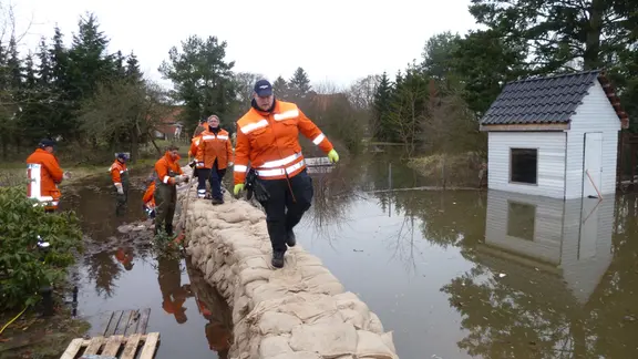 Feuerwehrleute gehen über einen Schutzdamm aus Sandsäcken.