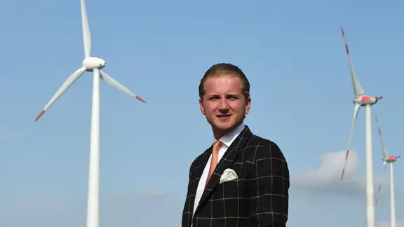 Hendrik Holt steht vor Windkraftanlagen.