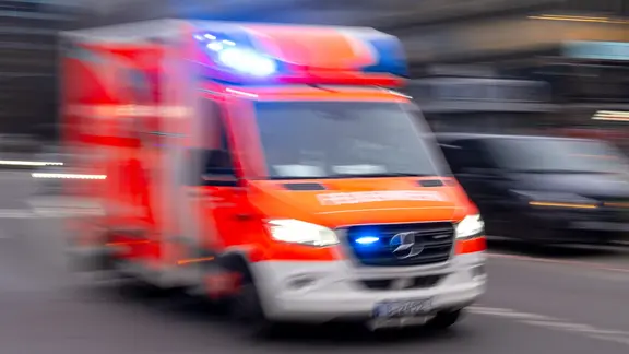 Ein Rettungswagen der Feuerwehr fährt mit Blaulicht zum Einsatz (Aufnahme mit Langzeitbelichtung).