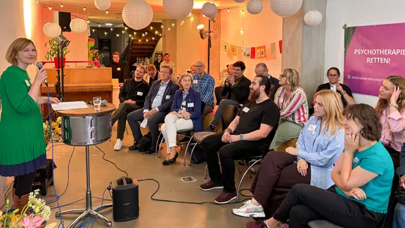 Menschen sitzen in einem geschmückten Raum bei dem offenen Austausch zum Thema Psychotherapie in Lübeck.