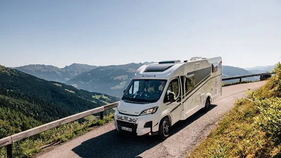 Ein Wohnmobil auf einer Straße in einer bergigen Landschaft (Themenbild).
