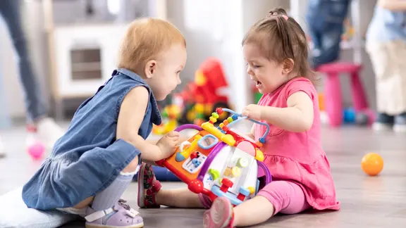 Symbolbild: Zwei Kinder streiten sich im Kindergarten um ein Spielzeug.