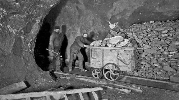 Bergarbeiter mit einem Förderwagen beim Erztransport in einem Stollen um 1910