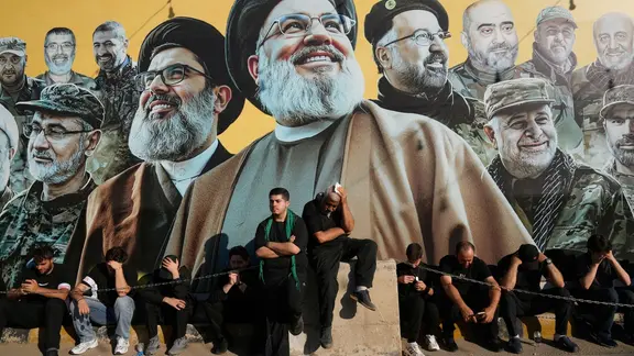 Libanon, Dahiyeh: Hisbollah-Anhänger sitzen vor einer riesigen Plakatwand die ihre Führer Sayyed Hassan Nasrallah, Hashem Safieddine und weitere Kommandanten zeigt.