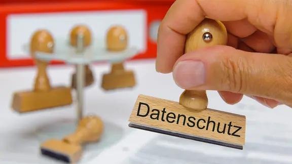 Eine Hand hält einen Stempel mit der Aufschrift "Datenschutz" in der Hand.