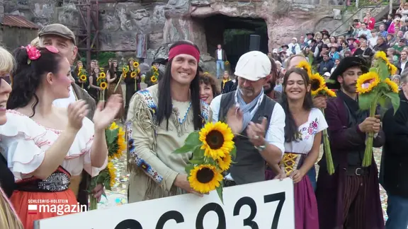 Alexander Klaws und das Ensemble steht mit Blumen vor dem Publikum.