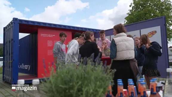 Eine Schülergruppe vor der Wanderausstellung "Stolen Memory" auf dem Schulparkplatz.