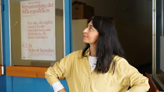 Muschda Sherzada vor einem Plaket an einem Durchgang