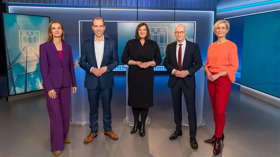 Dennis Thering (CDU), Katharina Fegebank (Grüne) und Peter Tschentscher (SPD) stehen vor dem TV-Triell mit den Moderatorinnen Susanne Stichler und Julia-Niharika Sen zusammen.