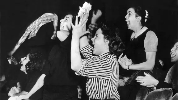 Weibliche Fans schreien bei einem Konzert in den 50er-Jahren vor Begeisterung.