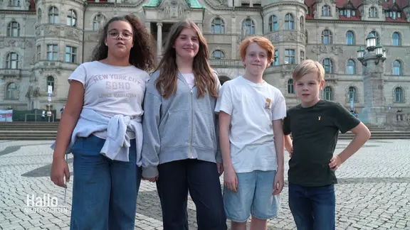 Vier Kinder stehen auf einem Marktplatz.
