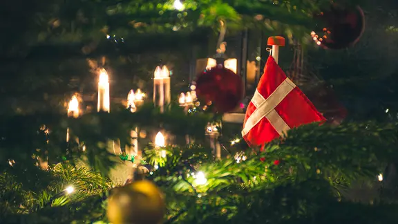 Ein Weihnachtsbaum von nahmen, mit Kerzen, Kugeln und einer Dänemarkflagge geschmückt.