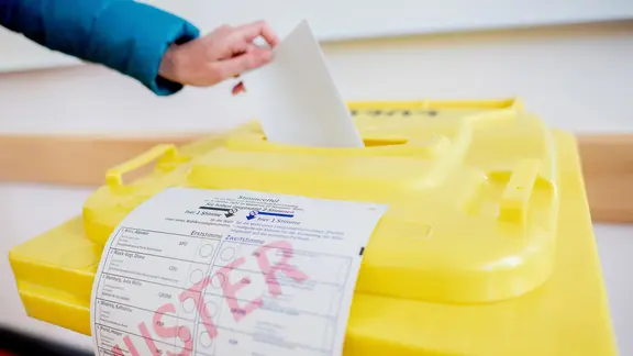 Eine Wählerin wirft in einem Wahlraum ihren Stimmzettel in eine Wahlurne.