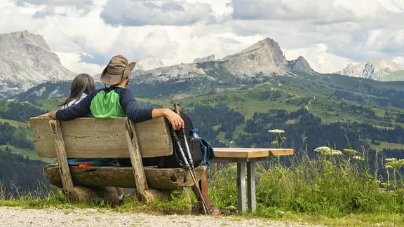 Wanderer ruhen sich auf einer Bank in den Dolomiten aus.