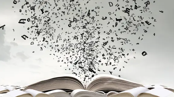 Buchstaben fliegen aus einem aufgeklappten Buch