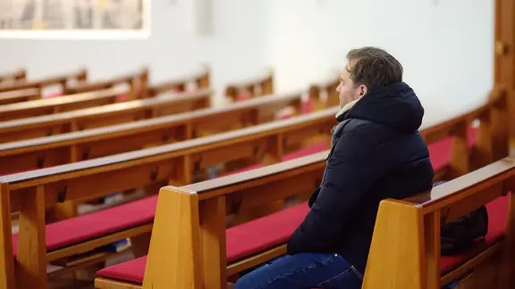 Ein einzelner Mann sitzt in einer Kirche.