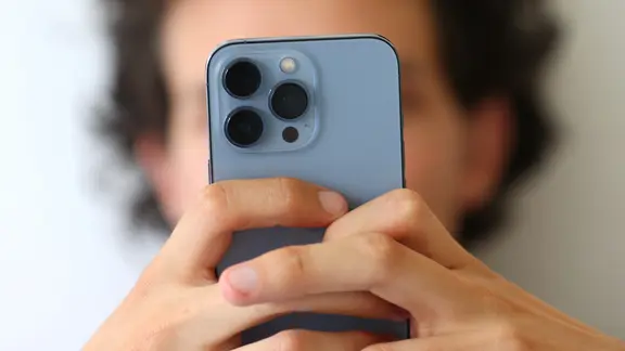 Eine Person schaut auf ihr Handy, die Handykamera ist auf den Betrachter gerichtet.