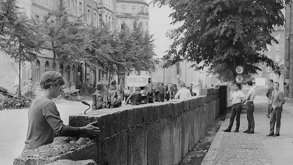 Von bewaffneten Volkspolizisten bewachte Bauarbeiter errichten die Mauer zwischen Potsdamer Platz und Lindenstraße.