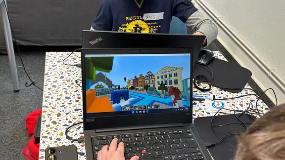 Zwei Jungen sitzen an Laptops und bauen im Videospiel "Minecraft" die Stadt Osnabrück nach.