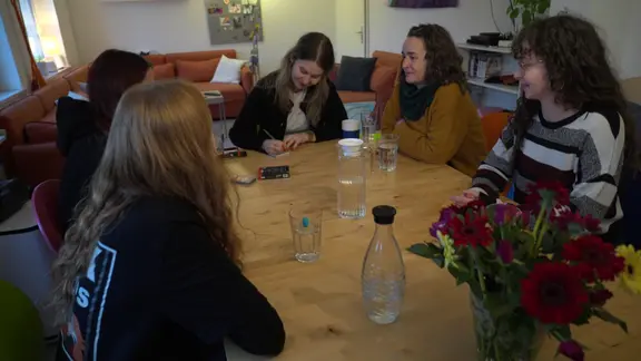 Eine Gruppe aus Frauen und Mädchen sitzt mit Karten an einem Tisch.
