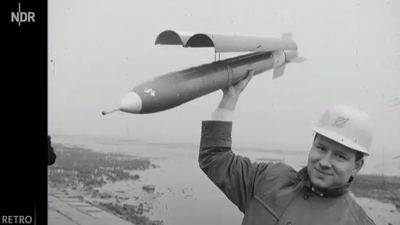 Ein Wissenschaftler hält am 23. März 1964 in Cuxhaven eine Versorgungsrekete in der Hand.