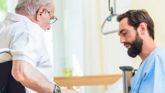Ein Pfleger betreut einen älteren Patienten.