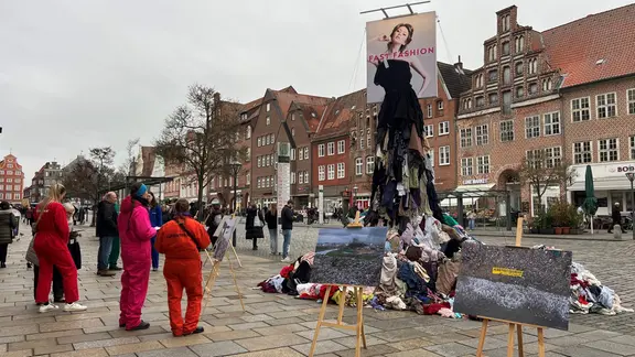 Aktivisten sammeln vor einer Statue aus alten Kleidern Unterschriften.