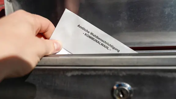 Eine amtliche Wahlbenachrichtigung in einem Briefkasten.