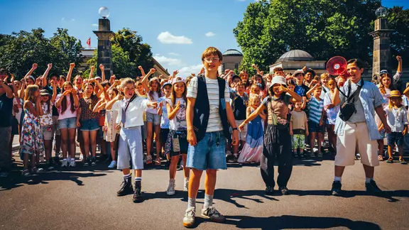 Szene aus dem Film "Emil und die Detektive": Eine Gruppe von Kindern steht im Vordergrund einer großen Menschenmenge und jubelt