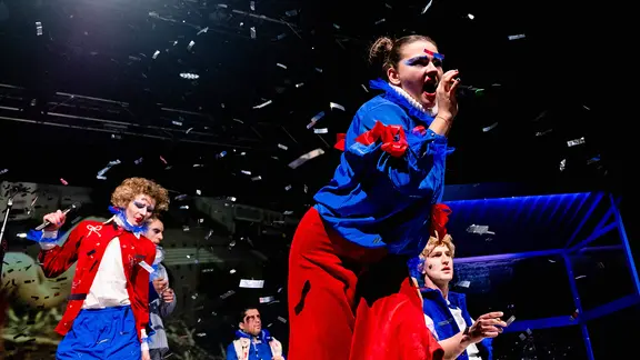 Junge Menschen mit blauer Jacke performen auf der Bühne