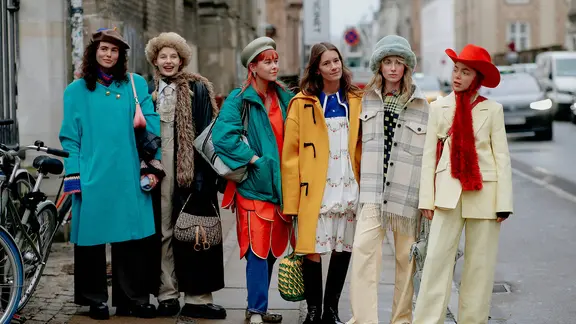 Zur Zeit der Kopenhagener Fashion Week stehen sechs junge Frauen in bunter Kleidung auf dem Gehweg.