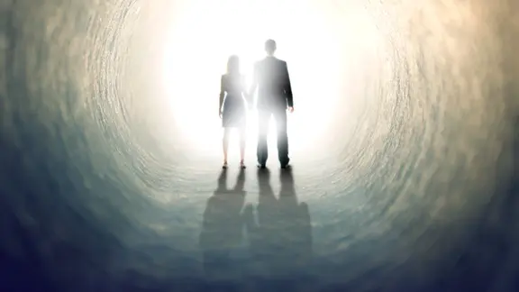 Am Ende des Tunnels stehen zwei Personen, Hand in Hand, dem Licht entgegen.
