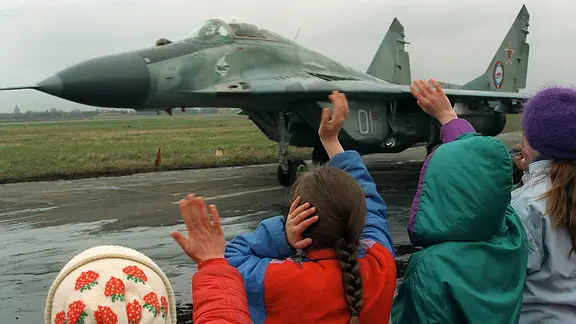 Kinder winken 1994 auf dem Militärflugplatz Pütnitz in Ribnitz-Damgarten einer startenden MiG-29 der Westgruppe der russischen Streitkräfte zu.