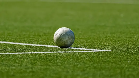Ein Spielball liegt auf der Linie eines Fußballfelds. 
