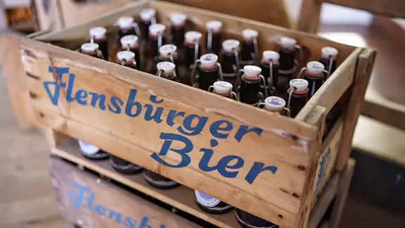 Flaschenbiere der Flensburger Brauerei stehen am 08.02.2021 in einer Holzkiste vor der Abfüllanlage.