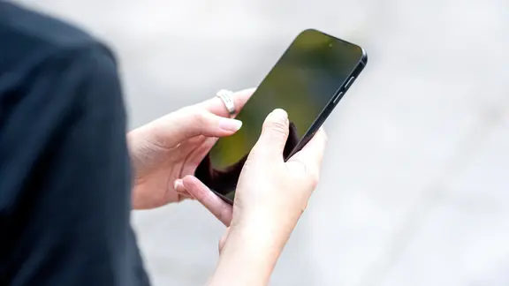 Eine Frau hält ein Smartphone in der Hand.