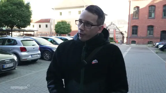 Ein Mann gibt ein Interview auf einem Parkplatz.