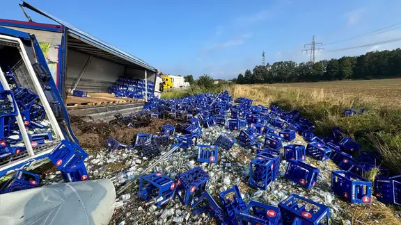 Wasserkisten aus einem verunglückten Lkw vliegen verteilt auf einer Wiese.
