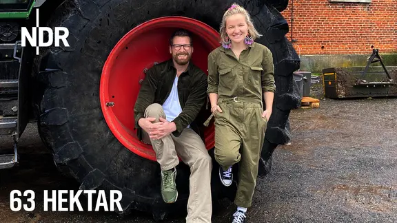 Landwirtin Maja Mogwitz und NDR Moderator Andreas Kuhlage sitzen in einem Treckereifen auf der Felge.