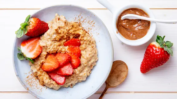 Ein Teller mit Porridge, darauf einige Erdbeeren.