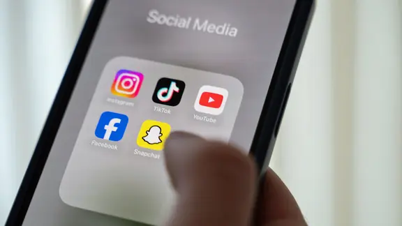 Eine Hand hält ein Smartphone mit den Apps Instagram, Facebook, TikTok, Snapchat und YouTube  