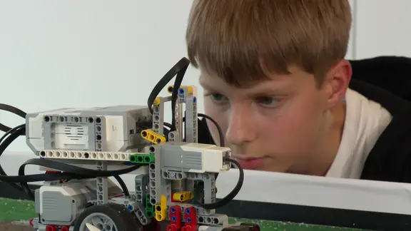 Ein Elfjähriger blickt auf seinen Lego-Roboter.