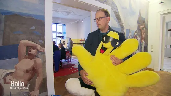 Martin Bron mit einer gelben, großen Plüschhand aus den 90er Jahren. 