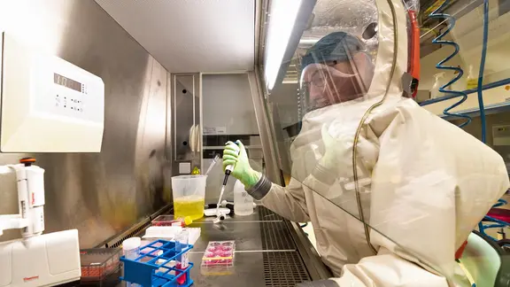 Im Hochsicherheitslabor des Robert Koch-Instituts (RKI) in Berlin stellt ein Mitarbeiter im Schutzanzug während eines Pressetermins die Untersuchung einer Probe nach. In dem Labor der höchsten Schutzstufe (S4) können Krankheitserreger wie Ebola-, Marburg-, Lassa- oder Nipahviren sicher untersucht werden. Das RKI ist das einzige Bundesinstitut im human­medizinischen Bereich mit einem S4-Labor. (Foto von 2018)