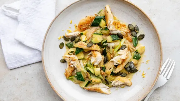 Ein Teller mit Spargelsalat mit Hähnchen und Zucchini.
